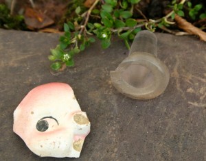 Found in a garden, part of a china face and a glass bottle stopper.