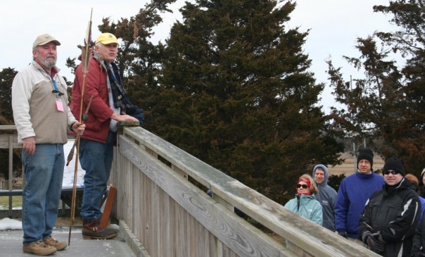 First day life - Gary Nolf holds an atlatl at left with Don Rankin and a group of more than 100 people who turned out for a first day hike.