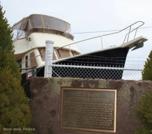 A modern boat near a sign that gives the history of the place, once revered as a Native American burial ground.