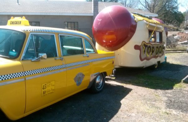 Who is the mystery man in the back seat of the vintage Checker cab that ferries Top Dog to and fro to Portland? 